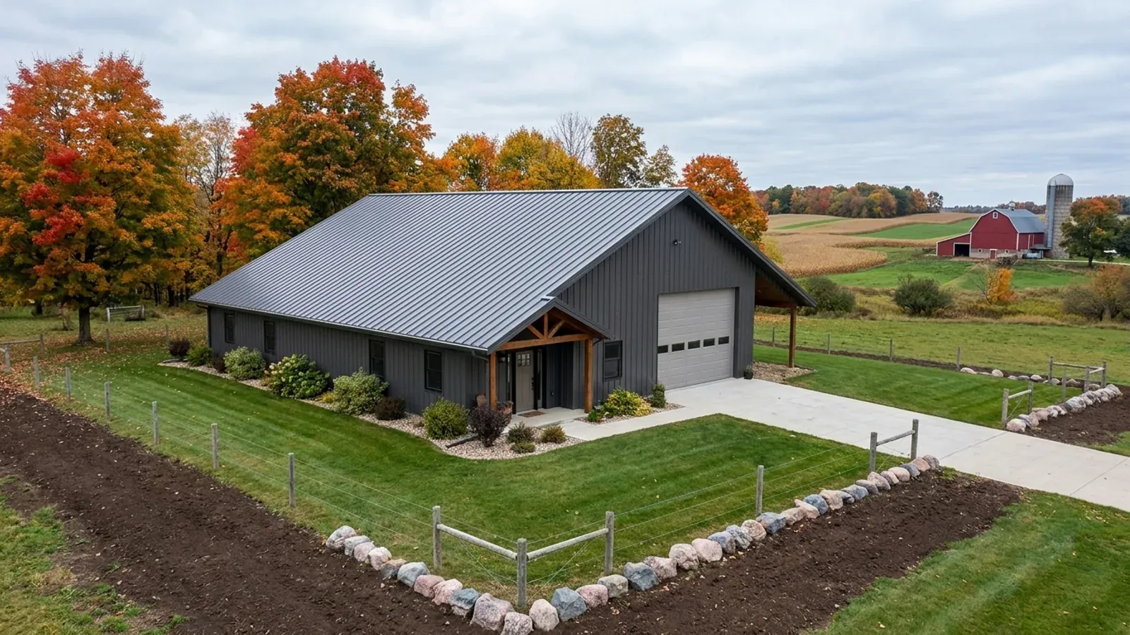 A completed 40x60 barndominium in autumn with a residential entry on one end and a wide shop door on the other under one continuous steep roof.